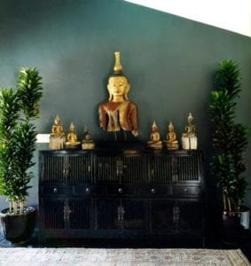 Wooden sideboard with slatted doors and levels of shelving inside, Buddha statues