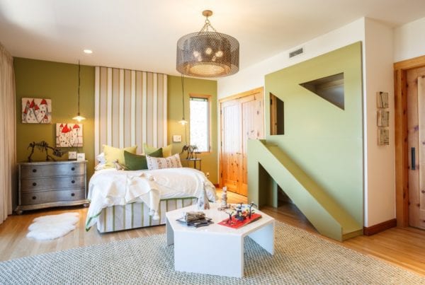 Child's room with green slide built into wall, striped wall hanging and playful design elements