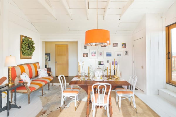 clean dining room with orange and white color scheme and wreath on wall 