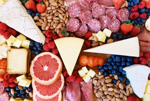 Colorful cheese board with meat, nuts and fruit
