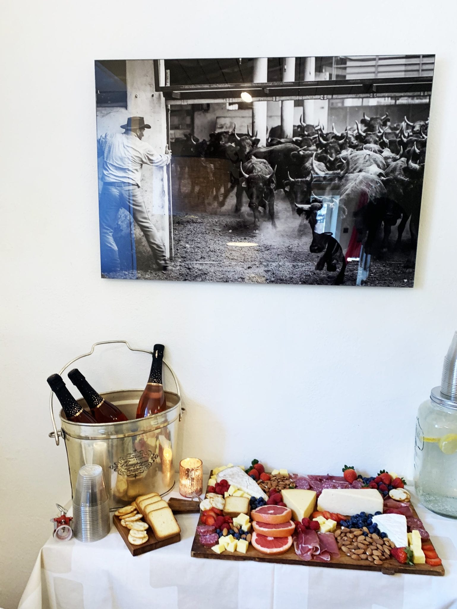 Colorful cheese board with meat, nuts and fruit on table with wine and black and white photo on wall