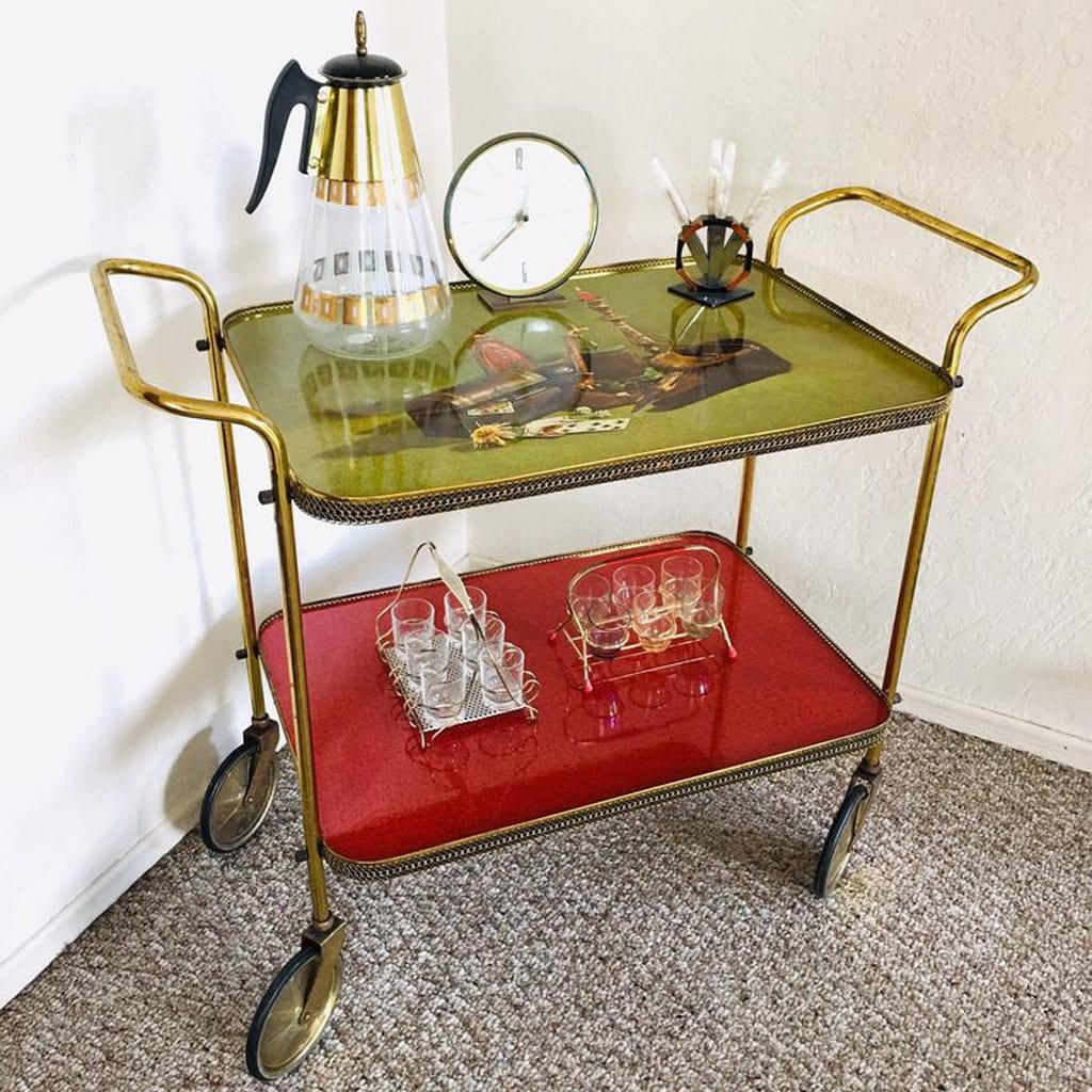 Antique bar cart with red and green trays and wheels