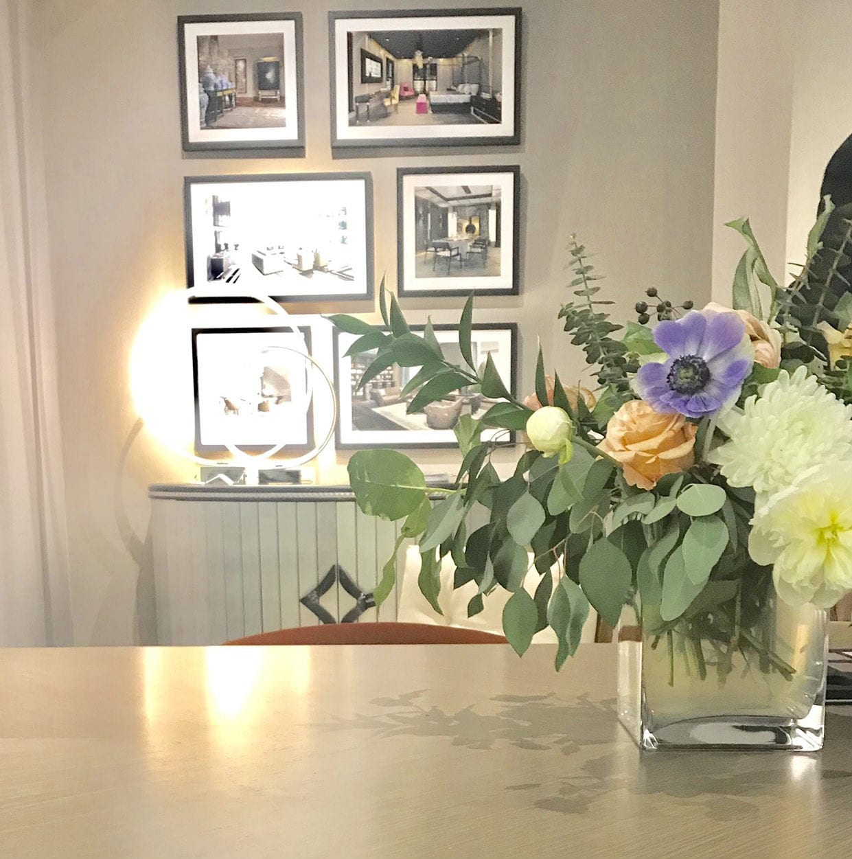 Table with flower arrangement and framed photographs in background