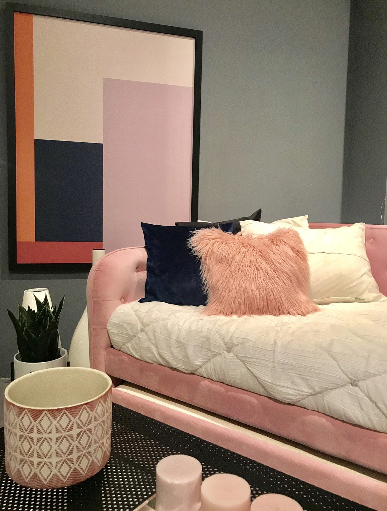 Pink daybed with white, pink and dark blue pillows and abstract painting