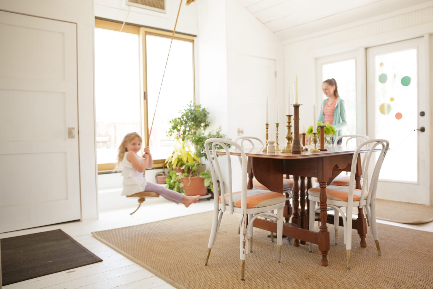 Private Tour A Scalable little girl on swing in house while mom watches